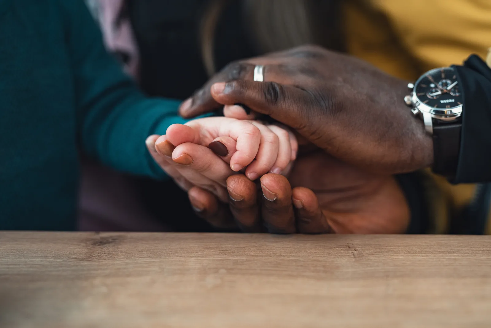 Mains de deux parents entourant la main d'un jeune enfant, illustrant l'arrivée d'un enfant adopté et le congé d'adoption