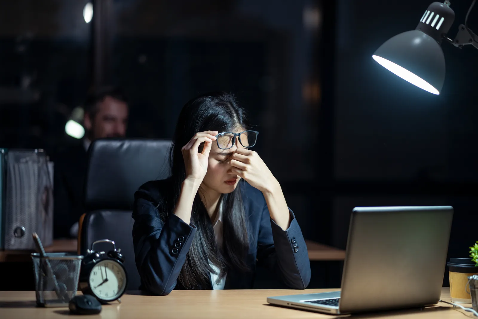 Salariée fatiguée à son bureau le soir, devant son ordinateur portable, après des heures supplémentaires