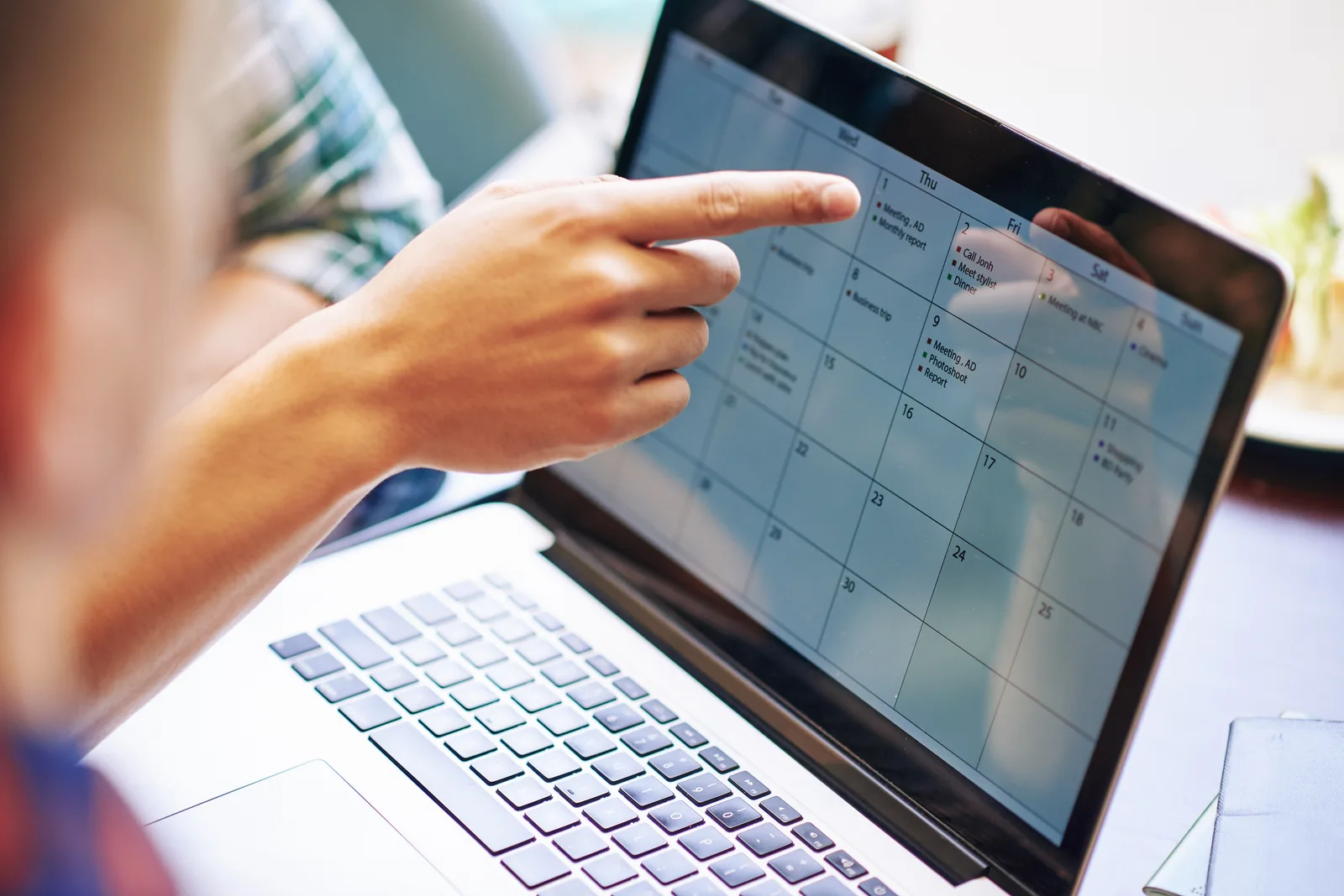 Calendrier de congés affiché sur un ordinateur portable, une main pointant un jour de la semaine